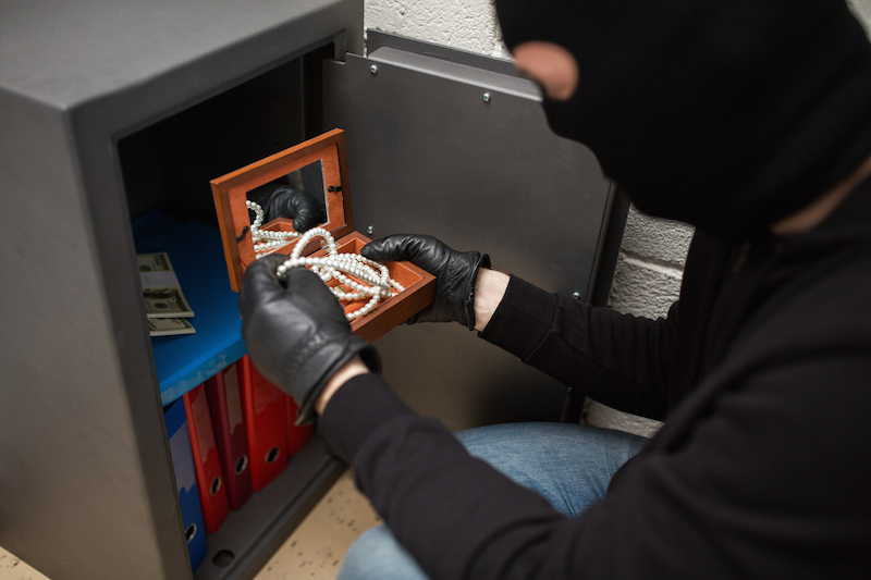 theft, burglary - thief in mask stealing valuables from safe at crime scene